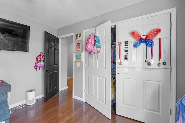 interior space featuring wood finished floors, baseboards, and a textured ceiling