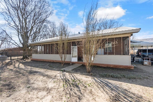 view of front of home with metal roof, brick siding, and a sunroom