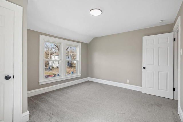 carpeted spare room featuring baseboards and lofted ceiling