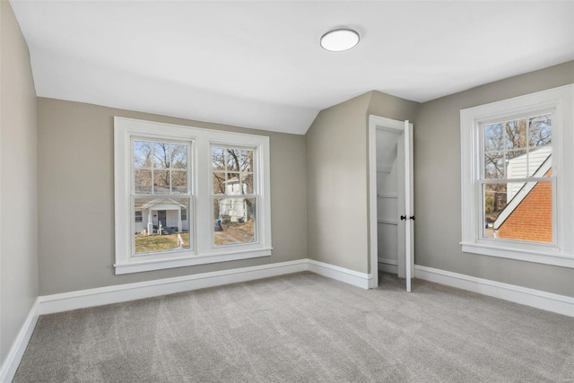 unfurnished bedroom featuring baseboards, multiple windows, carpet, and lofted ceiling