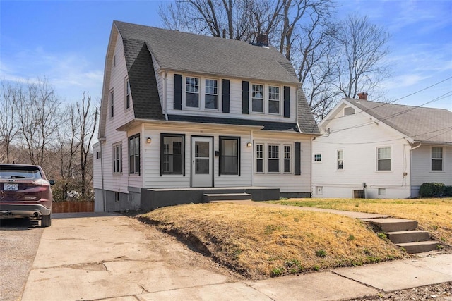 dutch colonial with a gambrel roof, central AC, roof with shingles, a chimney, and driveway