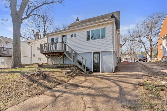 back of property with stairs, a deck, and a chimney