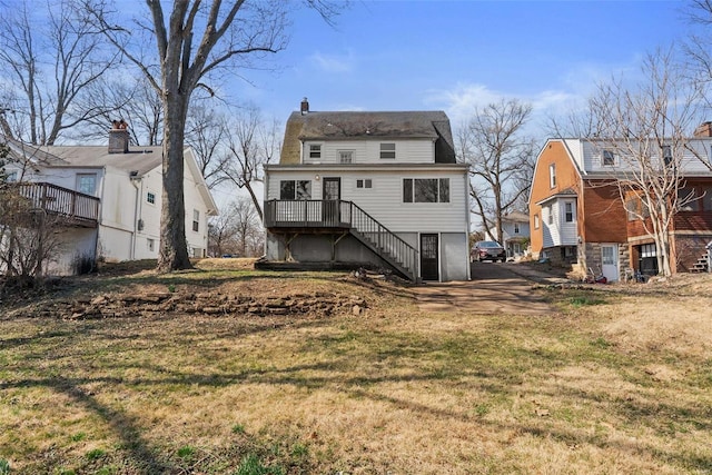 back of house with a chimney, stairs, and a yard