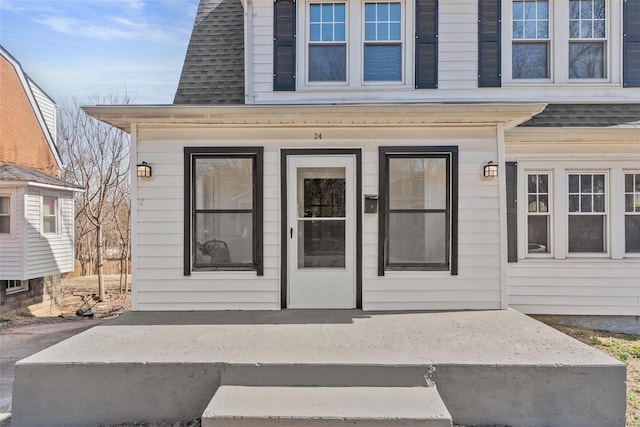 property entrance featuring covered porch and roof with shingles