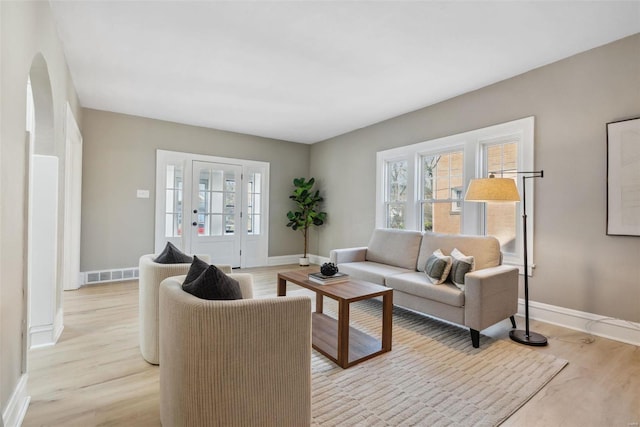 living room with visible vents, baseboards, and light wood-style floors