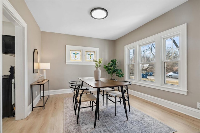 dining space featuring light wood-type flooring and baseboards