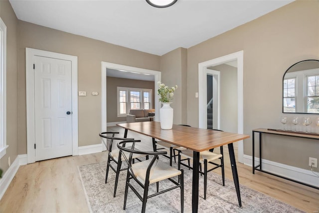 dining space featuring stairway, baseboards, and light wood-style floors