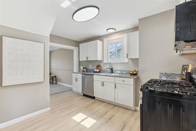 kitchen with a sink, stainless steel appliances, white cabinets, light wood finished floors, and baseboards