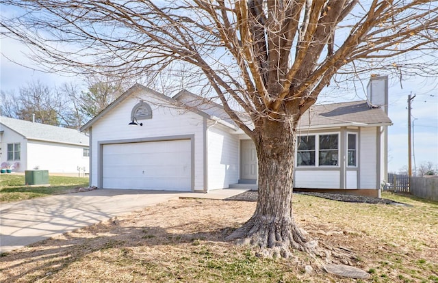 view of front facade with fence, concrete driveway, cooling unit, a chimney, and an attached garage