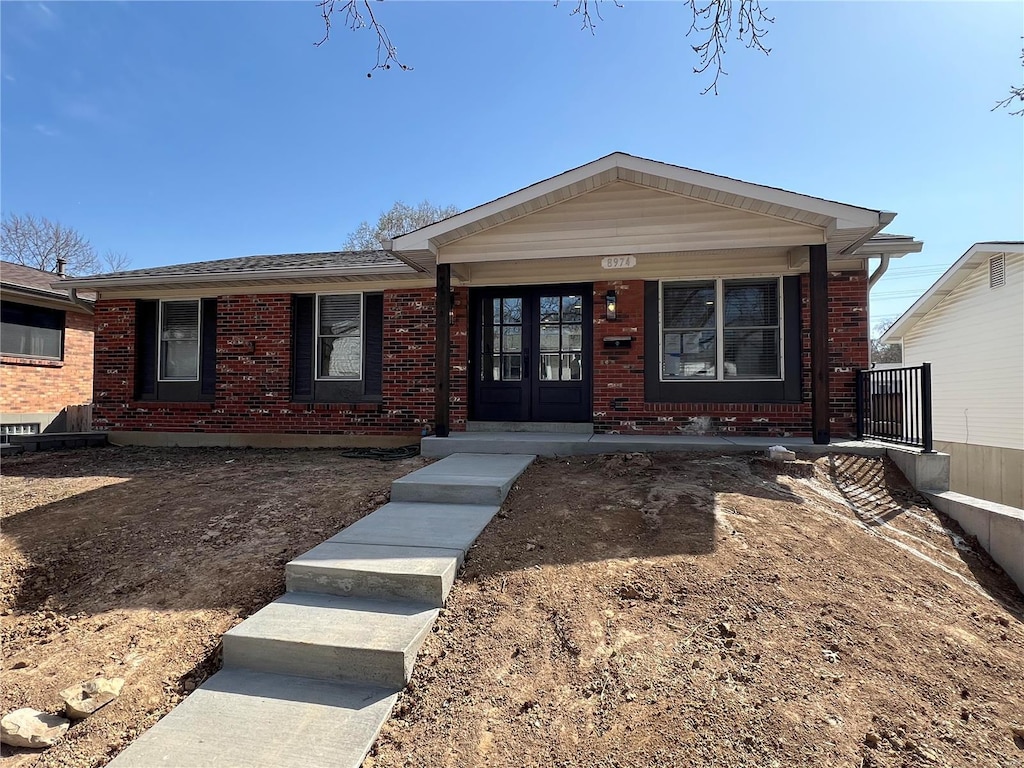 ranch-style house with brick siding, french doors, and roof with shingles