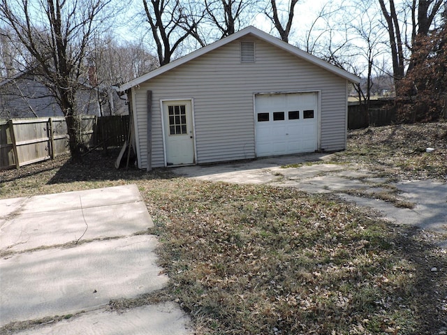 detached garage featuring driveway and fence