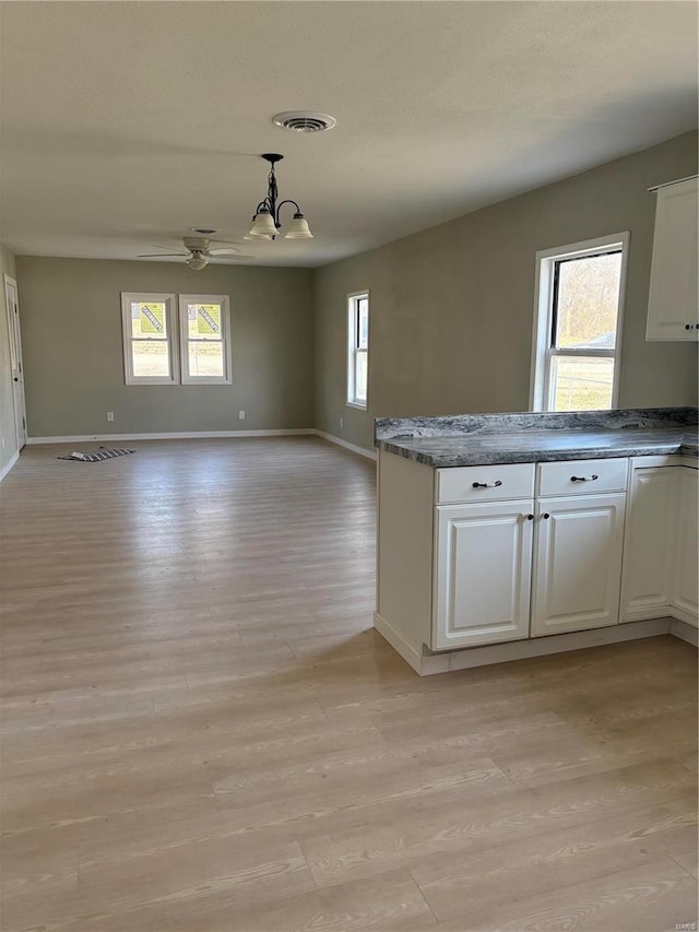 kitchen with plenty of natural light, white cabinets, light wood-type flooring, and open floor plan