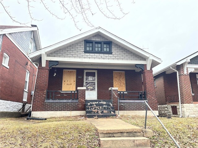 bungalow-style house featuring brick siding and a porch