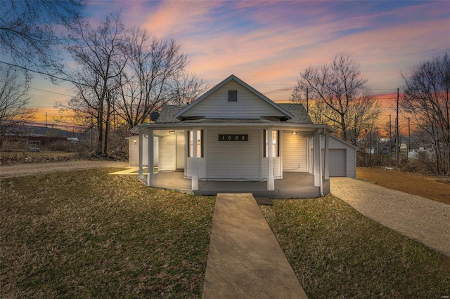 view of front of house with an outbuilding, driveway, a porch, a front lawn, and a garage