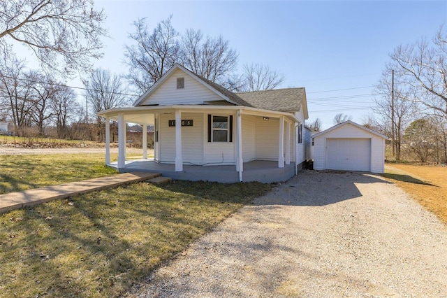 view of front facade with a front yard, gravel driveway, covered porch, an outdoor structure, and a detached garage