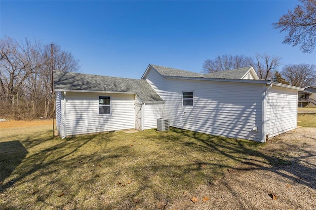 back of property with central air condition unit, a lawn, and roof with shingles