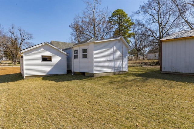 back of house featuring an outdoor structure, a storage shed, and a yard