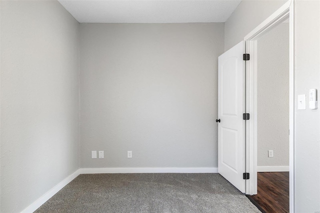 empty room featuring dark carpet and baseboards