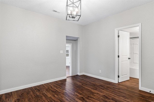 spare room featuring a notable chandelier, baseboards, and wood finished floors