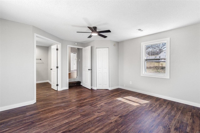 unfurnished bedroom with wood finished floors, visible vents, baseboards, a closet, and a textured ceiling