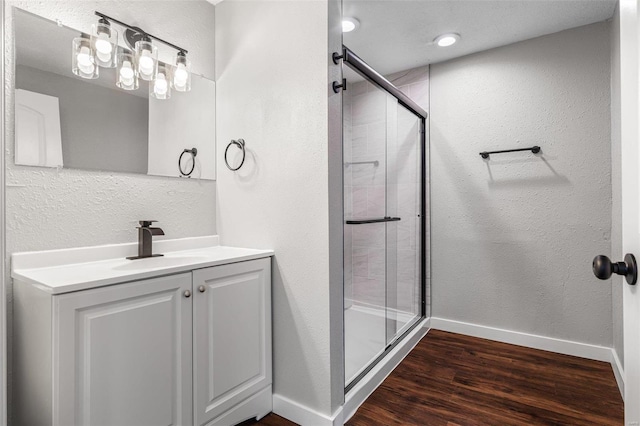 full bathroom with vanity, wood finished floors, baseboards, a stall shower, and a textured wall