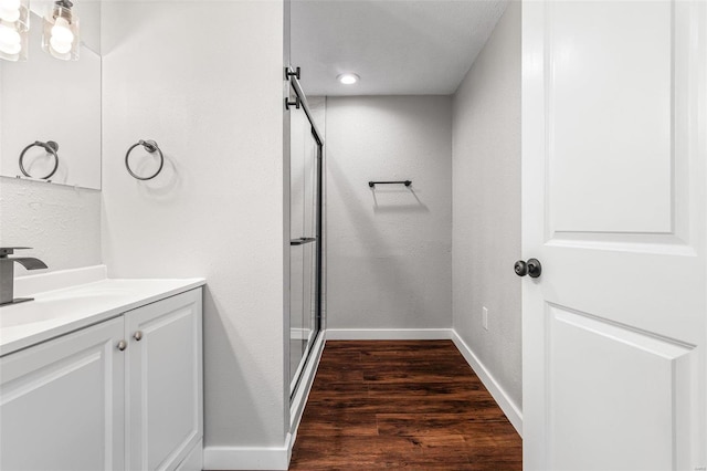 bathroom with vanity, wood finished floors, baseboards, and a stall shower