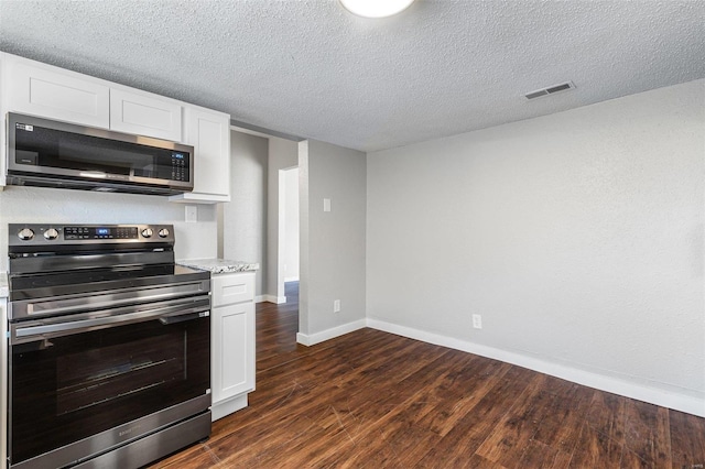 kitchen featuring baseboards, visible vents, dark wood finished floors, white cabinets, and appliances with stainless steel finishes