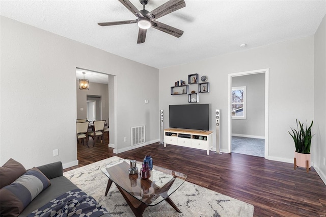 living room featuring visible vents, baseboards, a ceiling fan, and wood finished floors