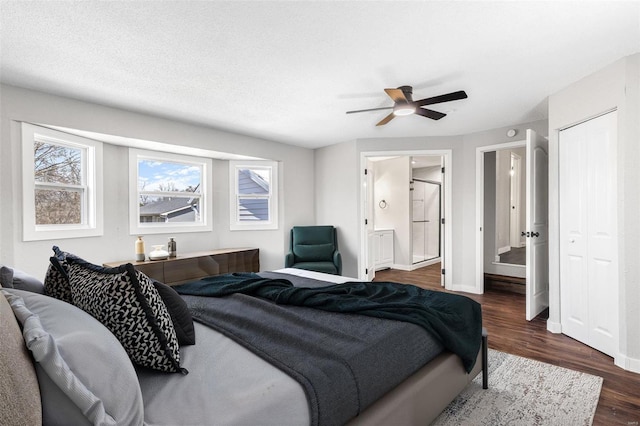 bedroom featuring dark wood-type flooring, ensuite bath, a closet, baseboards, and ceiling fan