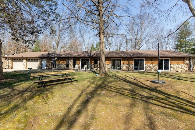 view of front of home featuring a front lawn, a garage, and stone siding