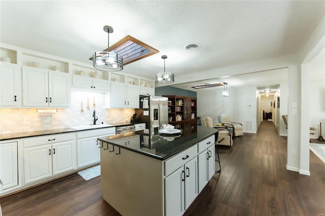 kitchen featuring visible vents, a sink, dark wood-type flooring, dark countertops, and backsplash