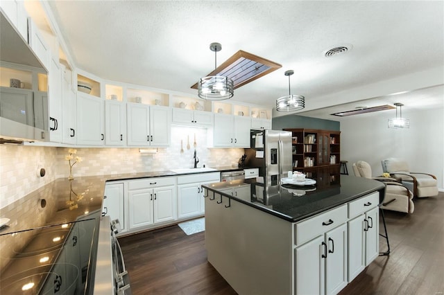 kitchen featuring visible vents, a sink, dark countertops, dark wood-style floors, and stainless steel appliances