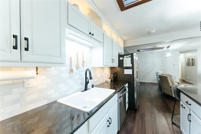 kitchen with a sink, dark countertops, dishwasher, and white cabinetry