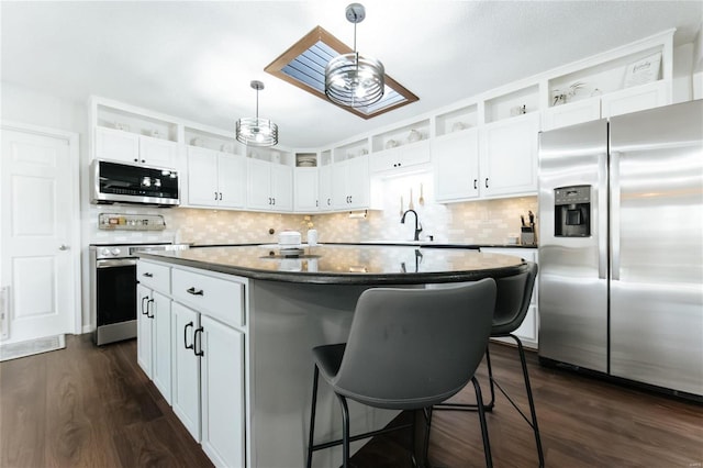 kitchen featuring a center island, dark wood-type flooring, a breakfast bar, appliances with stainless steel finishes, and white cabinets