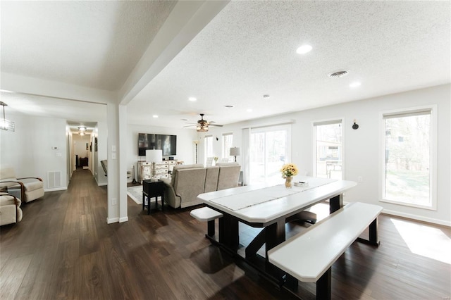 dining area with visible vents, a textured ceiling, and dark wood finished floors