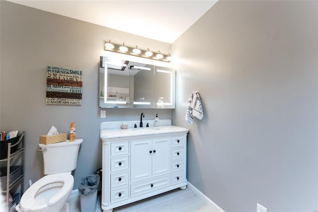 bathroom featuring vanity, toilet, and baseboards