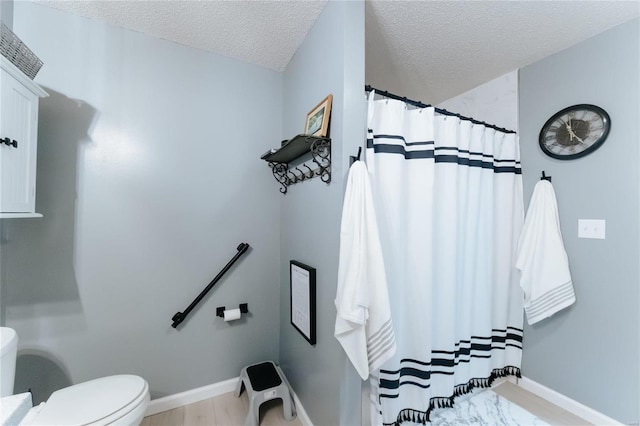 full bathroom with a shower with curtain, toilet, baseboards, and a textured ceiling