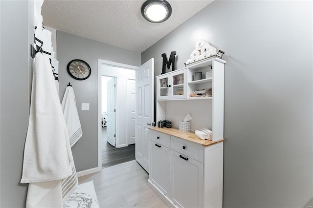 interior space featuring light wood-type flooring, baseboards, and a textured ceiling