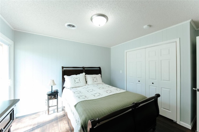 bedroom featuring dark wood finished floors, visible vents, a textured ceiling, and ornamental molding