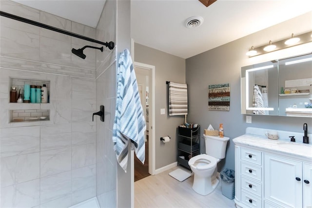 full bath featuring visible vents, toilet, wood finished floors, a tile shower, and vanity