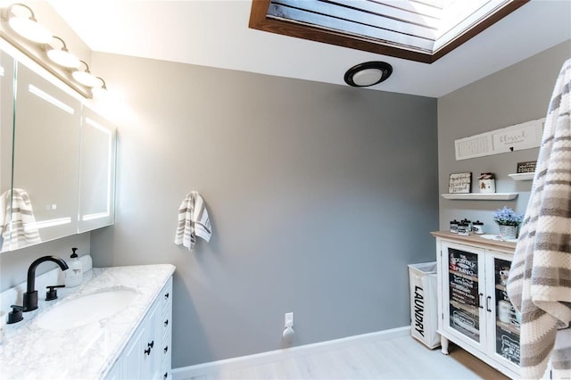 bathroom with vanity, a skylight, and baseboards