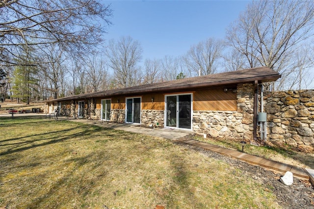 rear view of property with a yard and stone siding