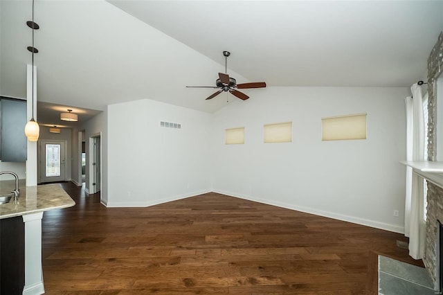 unfurnished living room featuring a stone fireplace, baseboards, dark wood-type flooring, and lofted ceiling