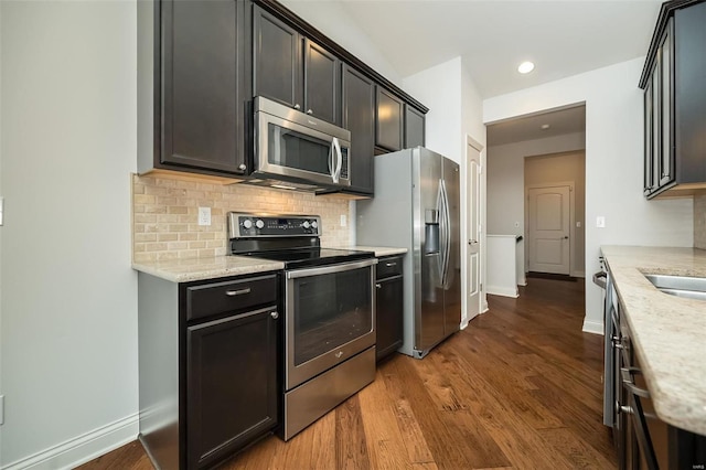 kitchen featuring backsplash, baseboards, light stone countertops, dark wood-style floors, and stainless steel appliances