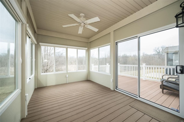 unfurnished sunroom with a ceiling fan, wood ceiling, and a healthy amount of sunlight