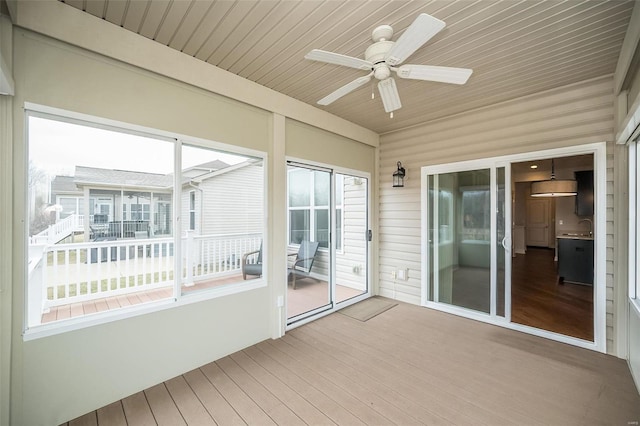 unfurnished sunroom featuring wooden ceiling, a ceiling fan, and a sink