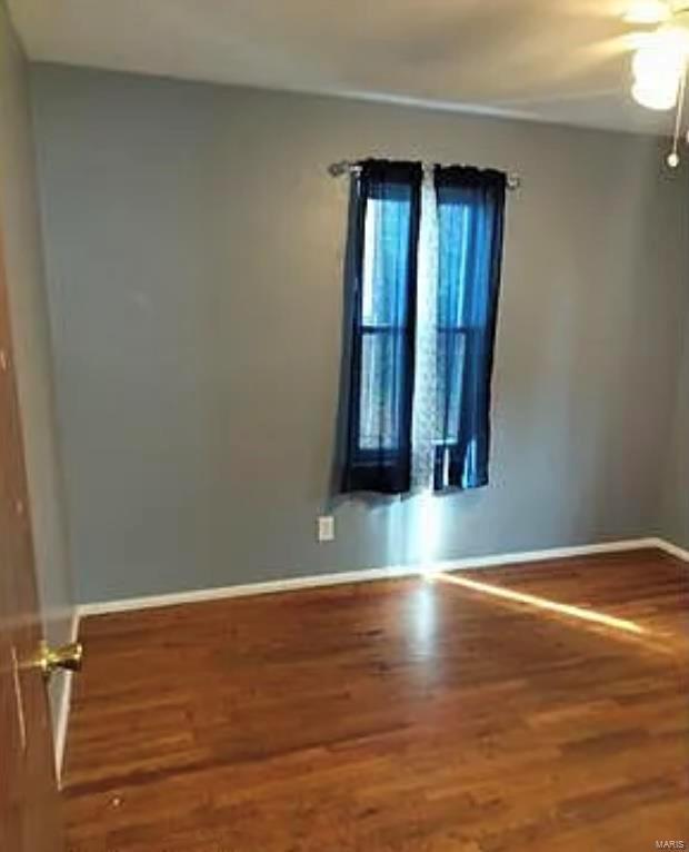 spare room with baseboards, wood finished floors, and a ceiling fan