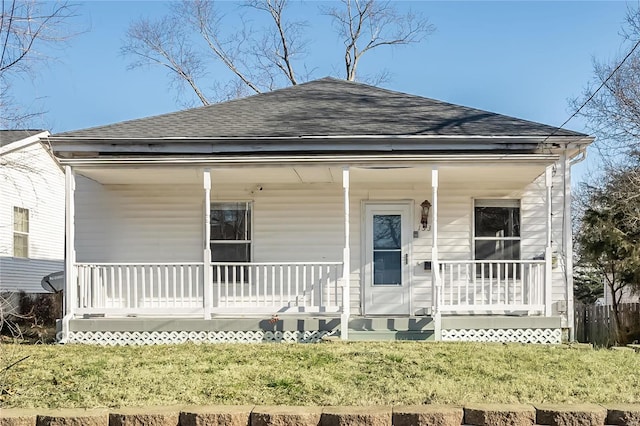 view of front facade featuring roof with shingles, covered porch, and a front lawn