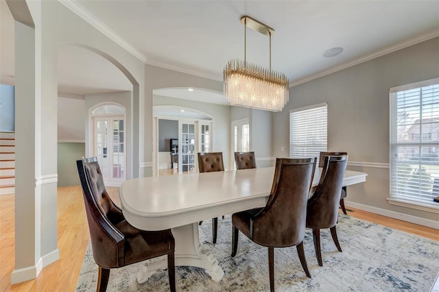 dining room featuring crown molding, a notable chandelier, a healthy amount of sunlight, and light wood-type flooring