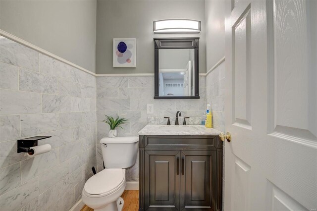 bathroom with toilet, tile walls, wood finished floors, and vanity